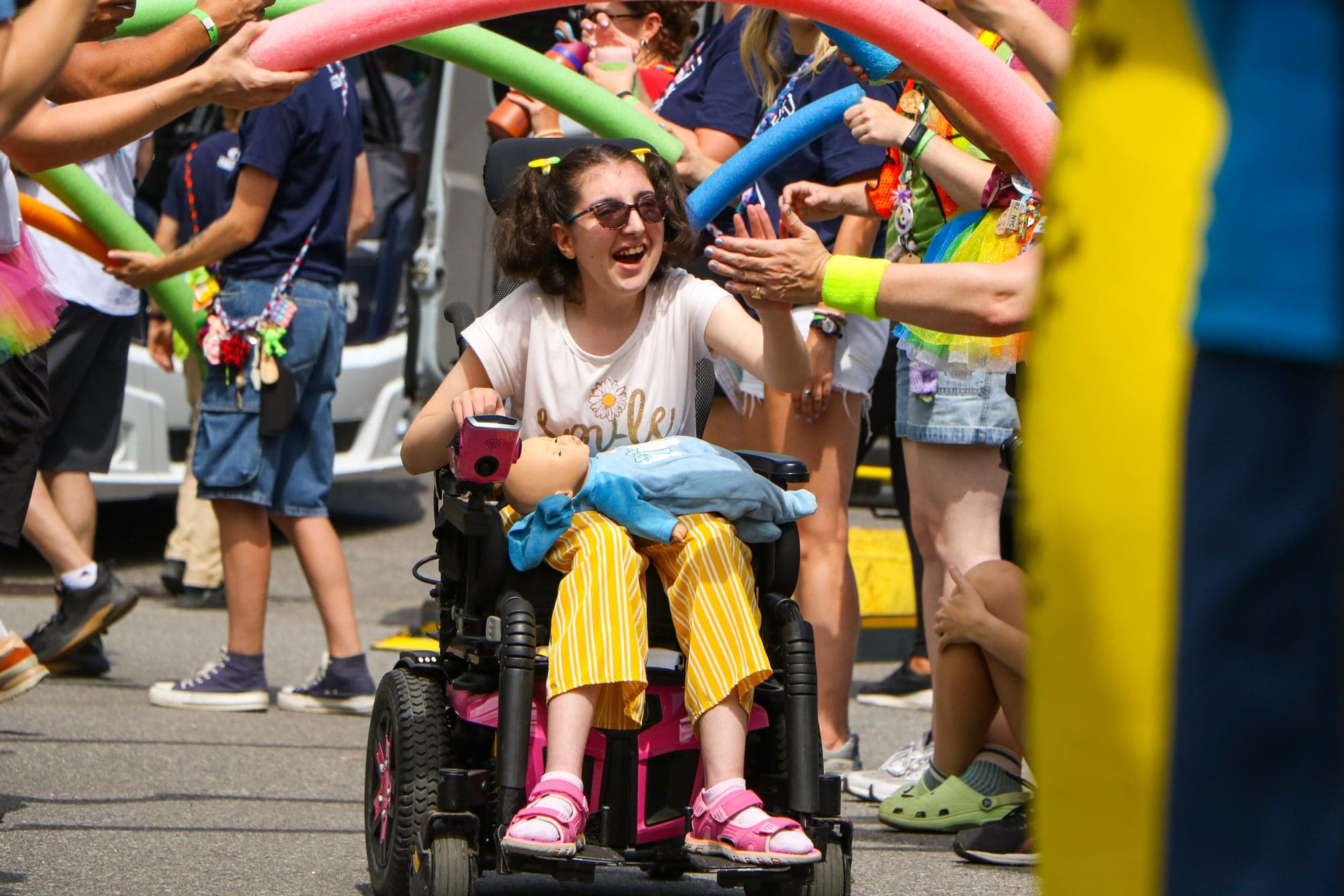 A camper is cheered through a tunnel of pool noodles as they arrive at a Campfire Circle event.